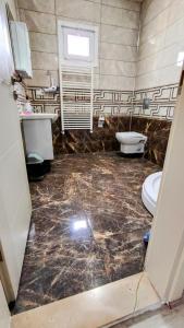 a bathroom with a marble floor and a toilet and sink at elva suites ardeşen in Ardeşen