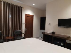 a hotel room with a bed and a desk and a television at Hotel Cepu Indah 2 in Cepu