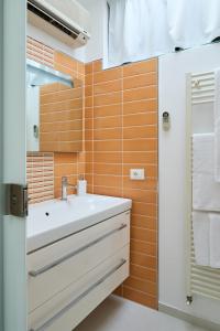 uma casa de banho com um lavatório branco e azulejos laranja em Mari Lifestyle em Fano
