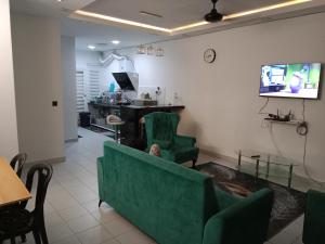 a waiting room with green chairs and a flat screen tv at Iyad Guest House in Banting