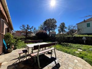 un tavolo da picnic e una panca su un patio di Maison de village vue mer et montagne a Sari Solenzara