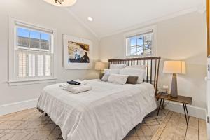 ein weißes Schlafzimmer mit einem großen Bett und zwei Fenstern in der Unterkunft Downtown Steps to Waterfront "The Garden" in Newburyport