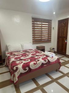 Schlafzimmer mit einem Bett mit einer roten und weißen Decke in der Unterkunft Stefanie Grace Paradise Inn in Loboc