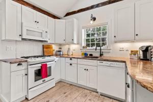 a white kitchen with white appliances and a wooden floor at The Garden Downtown Steps to Waterfront in Newburyport
