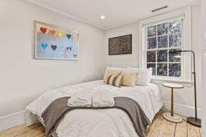 a white bedroom with a bed and a window at The Garden Downtown Steps to Waterfront in Newburyport