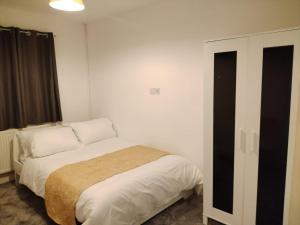a bedroom with a bed in a white room at Thales Home FFDblBath6 in Barking
