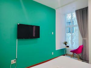 Zimmer mit einer grünen Wand und einem Flachbild-TV in der Unterkunft Adventure Hotel in Ho-Chi-Minh-Stadt