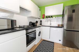 a kitchen with white cabinets and a stainless steel refrigerator at Spacious & modern 3 bed, 10 min to beach, parking - Lyell House in Poole