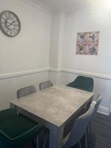 a table and chairs in a room with a clock at Modern 4 Bed House for 9 guests in Tilbury