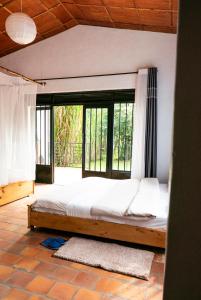 a bedroom with a bed with a large window at Susa Gardens in Ruhengeri