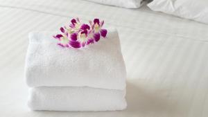 a white towel with purple flowers on a bed at Relax Inn Bloomsburg in Bloomsburg