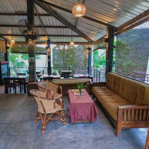 un porche cubierto con sofás, sillas y mesas en Tea Cottage Resort and Spa, en Nawalapitiya
