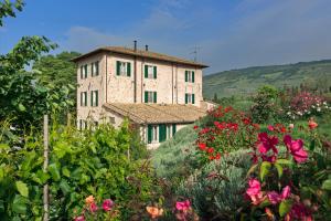 a building in the middle of a garden with flowers at Agriturismo Cuore Verde Olmo in Spello