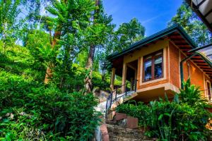 una casa en una colina con árboles en el fondo en Tea Cottage Resort and Spa, en Nawalapitiya
