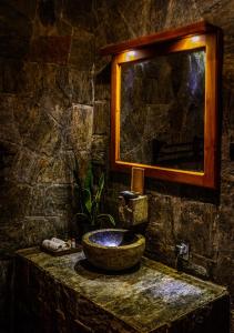 Baño de piedra con lavabo y espejo en Tea Cottage Resort and Spa, en Nawalapitiya