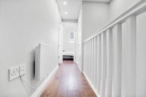 un pasillo con paredes blancas y suelo de madera en 7 Bedroom house with Garden, en Londres