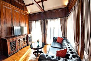 a living room with a leather couch and a table at Buri Sriping Riverside Resort & Spa in Chiang Mai