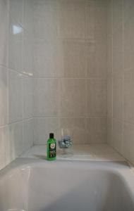 a green bottle of soap sitting on top of a bath tub at Estrela de mar in O Grove