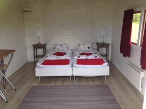 two beds in a white room with two tables at Burträsk Camping och Stugby in Burträsk