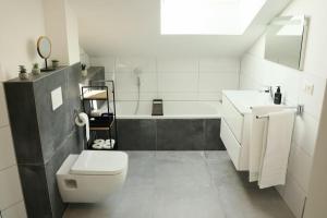 ein Badezimmer mit einem WC, einem Waschbecken und einer Badewanne in der Unterkunft WIESENglück in Altusried