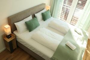 ein weißes Bett mit grünen Kissen und einem Fenster in der Unterkunft WIESENglück in Altusried