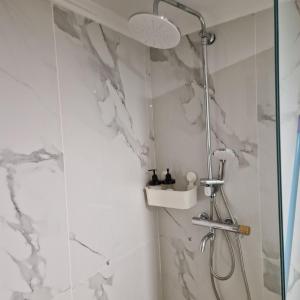 W łazience z białymi marmurowymi ścianami znajduje się prysznic. w obiekcie N&S Apartment B w mieście Edesa
