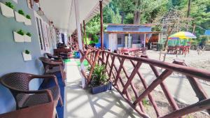 a balcony of a restaurant with chairs and tables at Giggling Goons Cabins & Kitchen in Kasol