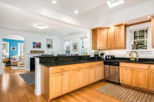 a kitchen with wooden cabinets and black counter tops at Steps to Downtown Rooftop Deck Flexible Temp Stay in Newburyport +57 photos