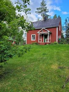 una casa roja en un campo con un patio verde en Torpet, en Liden