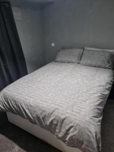 a bed in a bedroom with a white bedspread at Comfy 1st floor flat, sleeps 4 in London