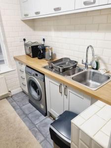 a kitchen with a sink and a washing machine at Comfy 1st floor flat, sleeps 4 in London