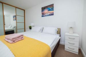a bedroom with a white bed and a yellow blanket at Dannyrex Apartments in Northampton