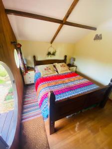 1 dormitorio con 1 cama con colcha colorida en Tyluna Cornish Cabin, en Praze an Beeble