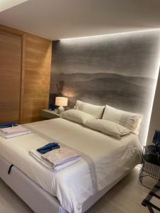 a bedroom with a large white bed with a painting on the wall at Appartamento Punta Grande - Scala dei Turchi in Realmonte