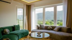 a living room with a couch and a table and windows at Green Ilidza Apartment in Sarajevo