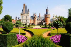 a castle with a garden with flowers in front of it at L'Art Déco - Maison + Parking (Portes de Chartres) in Jouy