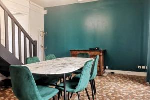 a dining room with a table and green chairs at L'Art Déco - Maison + Parking (Portes de Chartres) in Jouy