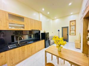 a kitchen with wooden cabinets and a table with yellow flowers at Agape Hotel & Căn hộ Đà Lạt in Da Lat