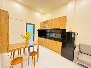 a kitchen with a wooden table and a black refrigerator at Agape Hotel & Căn hộ Đà Lạt in Da Lat
