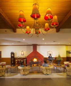 a lobby with a fireplace and people laying on tables at Gem Park Ooty in Ooty