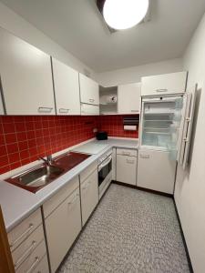 a kitchen with white cabinets and a sink and a refrigerator at Apartment Weßling in Weßling