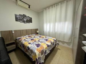 1 dormitorio con 1 cama con manta de flores en Praia De Palmas, apartamento 2 quartos, completo próximo a praia e todo comercio, en Governador Celso Ramos