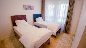 two twin beds in a room with a window at Green Ilidza Apartment in Sarajevo