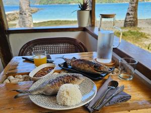 un tavolo con due pesci e riso e una vista sull'oceano di DK2 Resort - Hidden Natural Beach Spot - Direct Tours & Fast Internet a El Nido