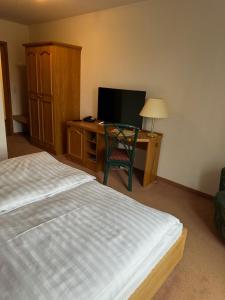 a bedroom with a bed and a desk with a television at Hotel am Spreebogen in Burg