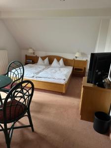 a bedroom with a bed and chairs and a tv at Hotel am Spreebogen in Burg