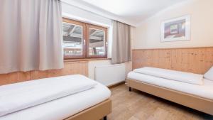two beds in a room with two windows at Hapimag Ferienwohnungen Saalbach in Saalbach-Hinterglemm