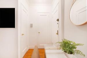 un bagno bianco con specchio e pianta in vaso di 105-1G Park Ave Location studio best value Sleeps3 a New York