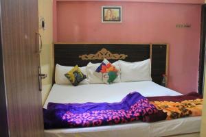 ein Schlafzimmer mit einem großen Bett mit weißer Bettwäsche in der Unterkunft Amudha Hotels & Restaurant in Yercaud