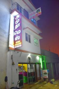 una tienda con letreros de neón al lado de un edificio en Amudha Hotels & Restaurant, en Yercaud